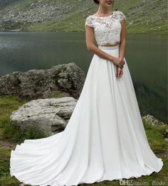 a woman standing in front of a lake wearing a wedding dress