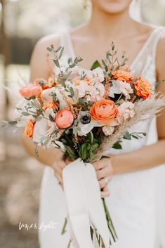 a woman holding a bouquet of flowers in her hands and wearing a white dress with an orange sash