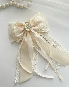 an ivory garter with pearls and ribbon attached to it, on a white surface