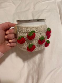 a woman is holding a coffee cup with strawberries on it and the lid has been crocheted