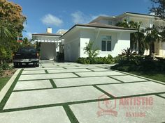 a car parked in front of a white house with grass on the driveway and palm trees