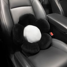 the interior of a car with black leather seats and a white flower shaped pillow on it