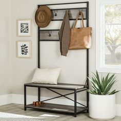 an entryway with a bench, coat rack and hat on the wall next to a potted plant