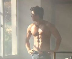 a shirtless man standing in front of a window with his hands on his hips