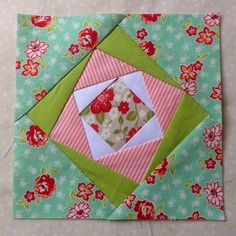 an origami quilted square with flowers and green fabric on the table top