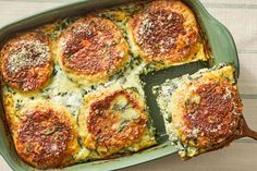 a green casserole dish filled with cheese and spinach covered in parmesan