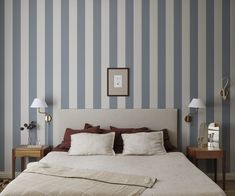 a bedroom with striped wallpaper and two lamps on either side of the headboard