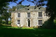 an old stone house sitting on top of a lush green field