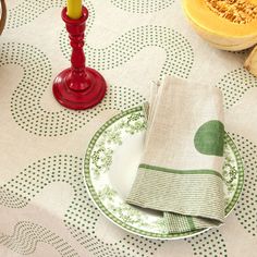 a table topped with plates and candles on top of a tablecloth covered in green dots