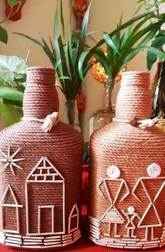 two brown vases sitting on top of a table next to plants and potted plants