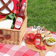 a picnic basket filled with food and drinks on top of a checkered table cloth