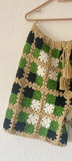 a crocheted green and white afghan hanging on a wall next to a wooden hanger