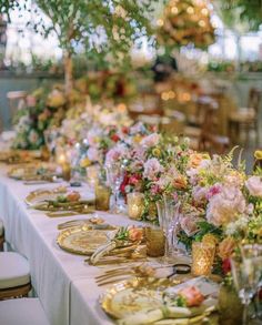 a long table is set with flowers and goldware for an elegant dinner party or reception