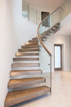 a spiral staircase with glass railing and wooden steps