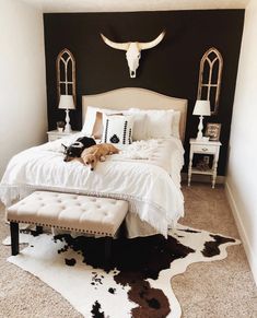 a dog laying on top of a bed in a room with black walls and white furniture