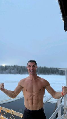 a shirtless man standing on a boat with his arms in the air and smiling