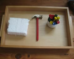 a wooden tray with a tool and marshmallows in it