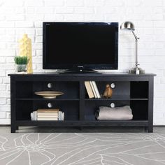 a flat screen tv sitting on top of a black entertainment center next to a white brick wall