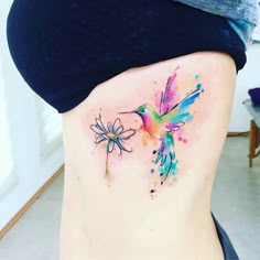 the back of a woman's stomach with watercolor hummingbird tattoos on it