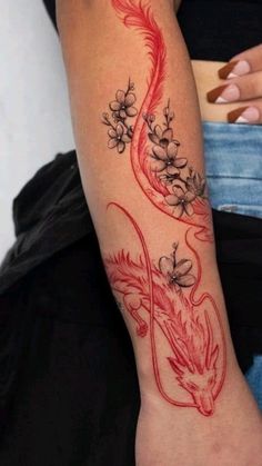 a woman's arm with a red dragon tattoo on the left side of her arm