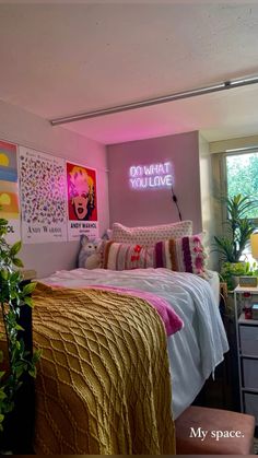 a bedroom with pink walls and yellow bedding in front of a neon sign that reads do what you love