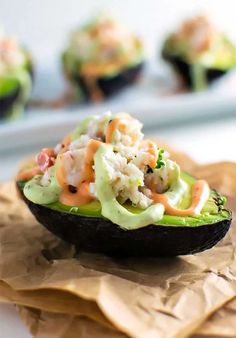 an avocado filled with shrimp salad on top of brown paper