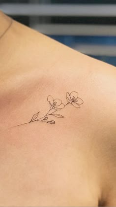 a small tattoo on the back of a woman's shoulder, with flowers growing out of it