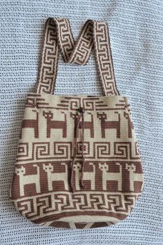 a brown and white purse sitting on top of a bed