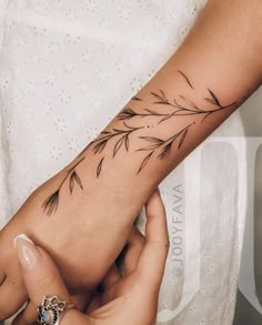 a woman's arm with a branch tattoo on the left side of her hand