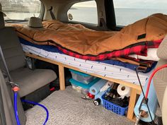 the inside of a van with a sleeping bag on it's bed and other items in the back