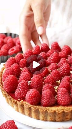 a person placing raspberries on top of a pie