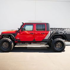 a red and black jeep parked in front of a building