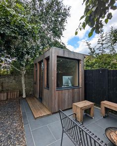 a small wooden building sitting in the middle of a yard next to a fire pit