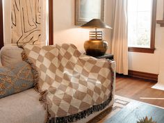 a living room with a checkered blanket on the couch and a lamp next to it