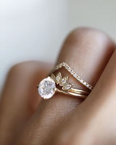 a woman's hand with a diamond ring on top of her finger and an engagement band