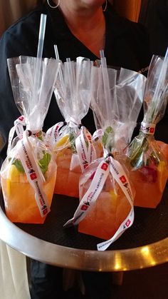 a woman is holding a tray with some fruit wrapped in plastic bags