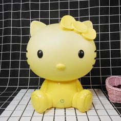 a yellow hello kitty sitting on top of a tiled floor