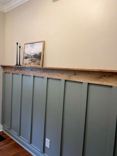 an empty room with wood paneling on the wall and a framed photograph above it