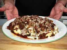 a person holding a plate with food on it and sauce drizzled over the top