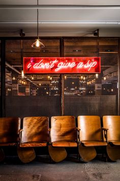 a row of chairs sitting in front of a neon sign