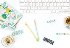 a keyboard, pen, and other office supplies on a white desk with a flowery background