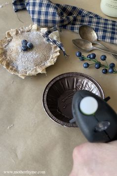 a piece of pie sitting on top of a table next to spoons and blueberries