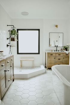 a white bathroom with hexagonal tile flooring and large window above the bathtub