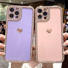 two women holding up their iphone cases with heart shaped jewels on the front and back