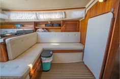 the inside of a sailboat with a couch and storage container on the floor next to it