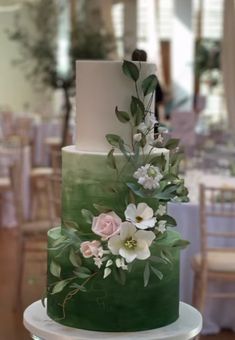 a three tiered cake with flowers and greenery on it