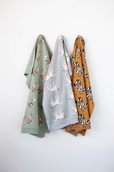 three towels are hanging on the wall next to each other with animals printed on them