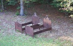 three metal beds sitting in the middle of a field next to some trees and grass