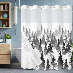 a bathroom with a shower curtain that has trees on it