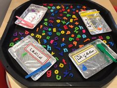 a black tray with plastic letters and numbers on it, along with some colored pencils